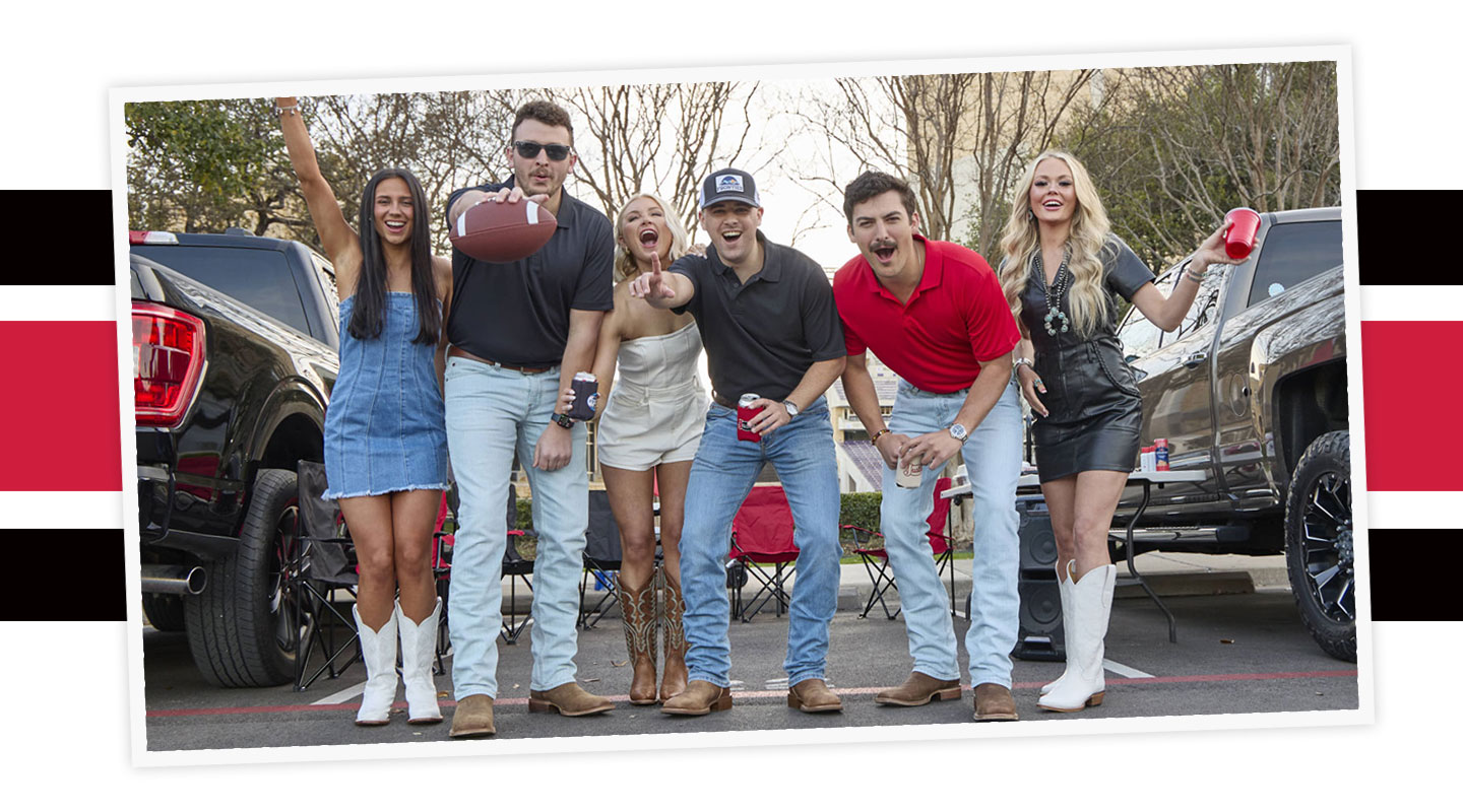 A group of young adults wearing Justin western boots are tailgaiting at a game.